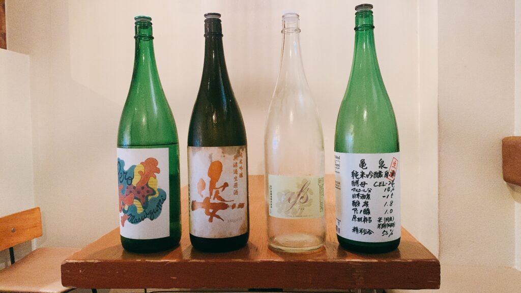 Four Japanese sake bottles with different labels lined up on a table, showing the label variety beginners face when picking the best sake for beginners